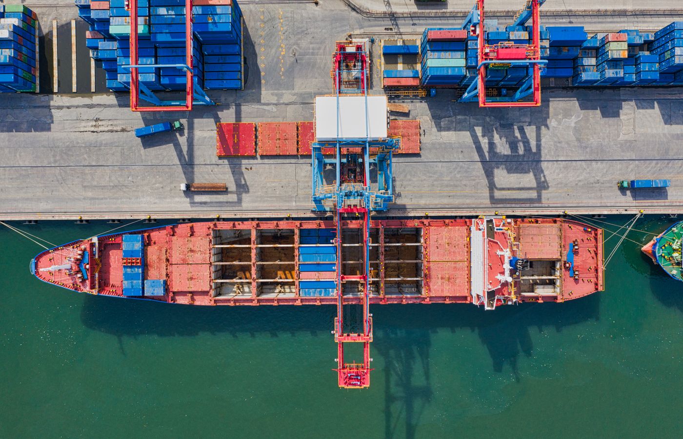 Containers stacked on a ship at a working port, seen from above
